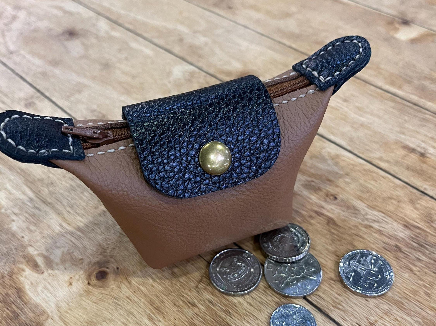 Elegant leather mini purse with coin on wooden table