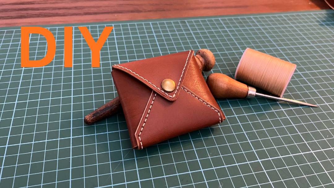 DIY brown leather envelope shape coin purse with sewing tool on a cutting mat