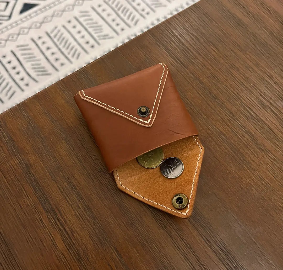 Brown DIY leather wallet with coins on a wooden surface