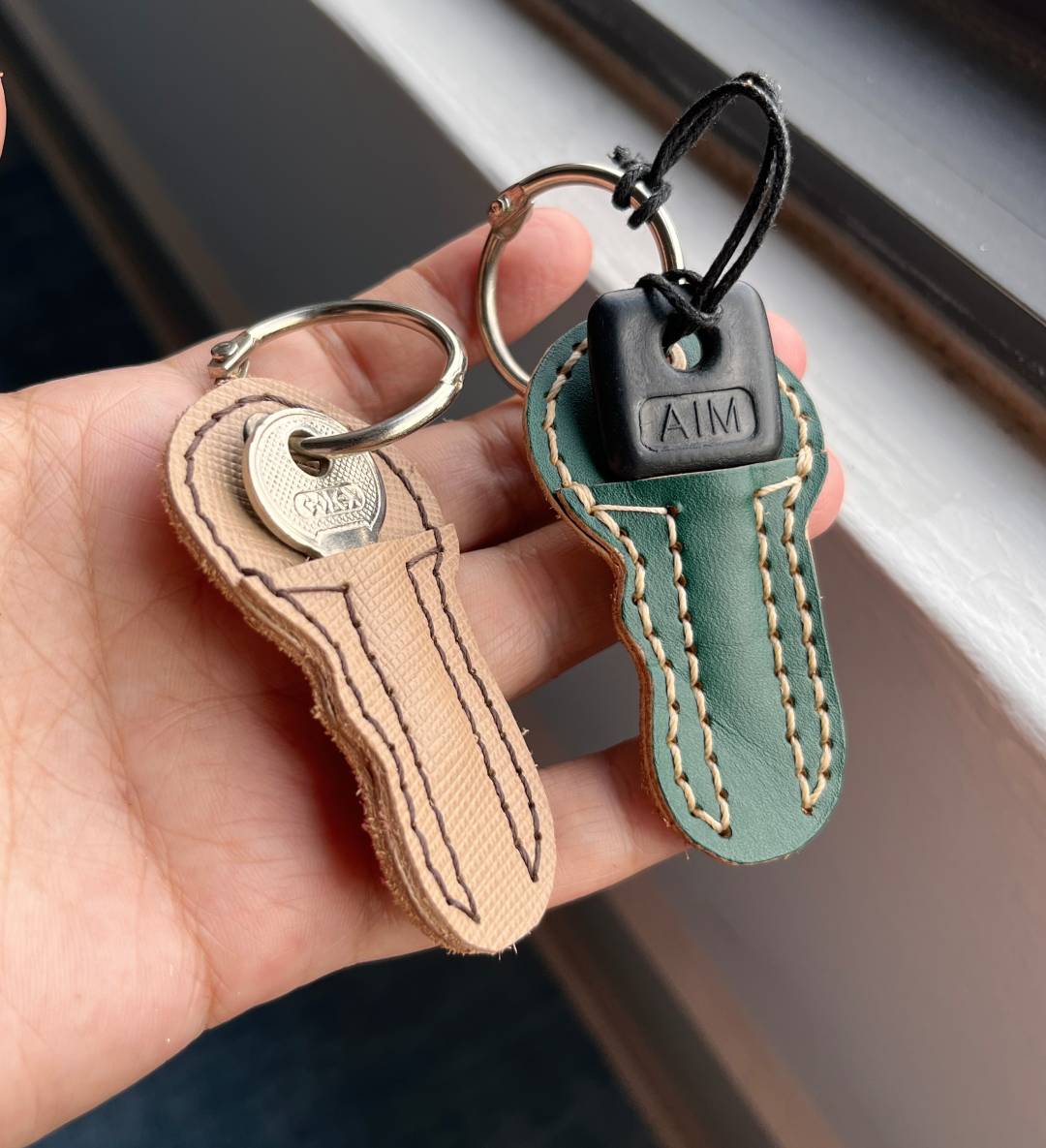hand holding 2 DIY leather key shaped keychain organizer 