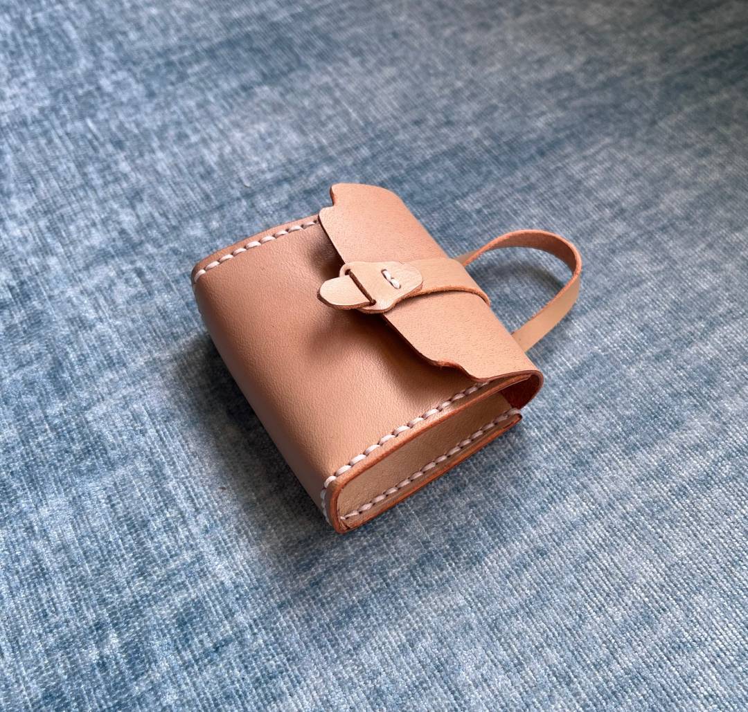DIY tiny brown leather bag with a strap on a blue denim background