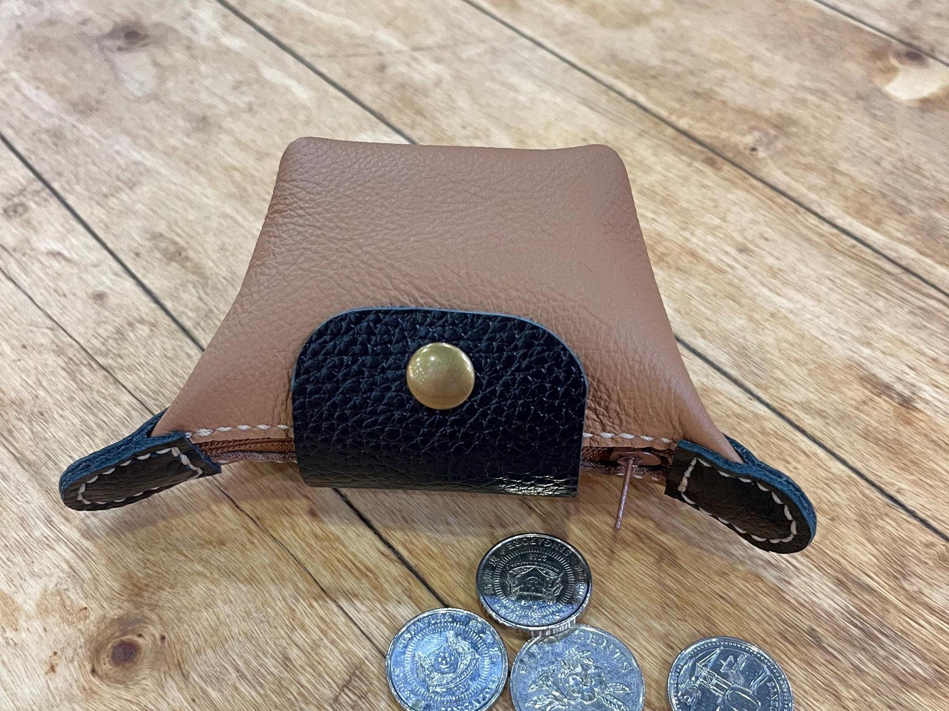 Close-out view of leather mini purse with coin laying on wooden table