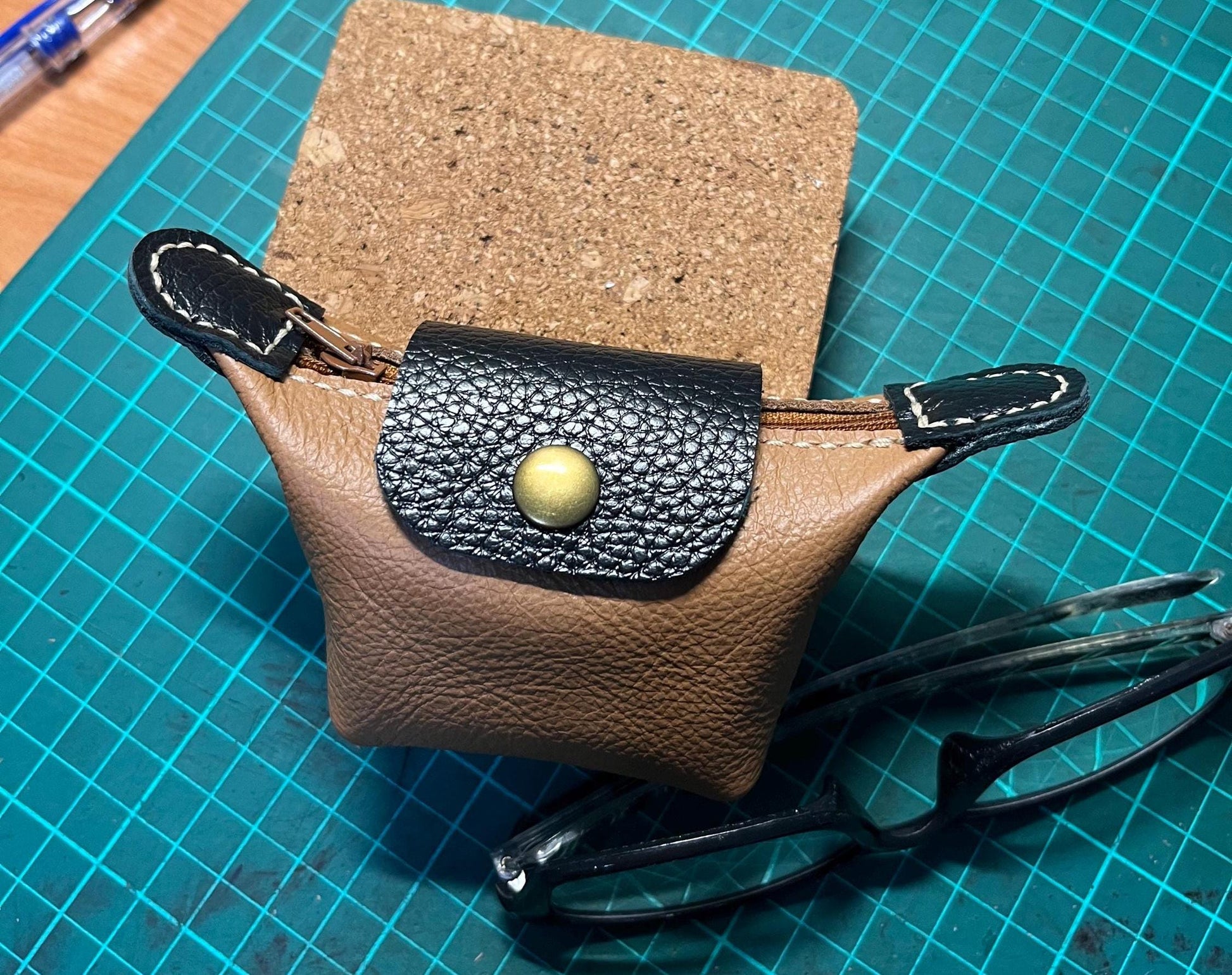 Another view of completed elegant leather mini purse with a pair of glasses beside purse