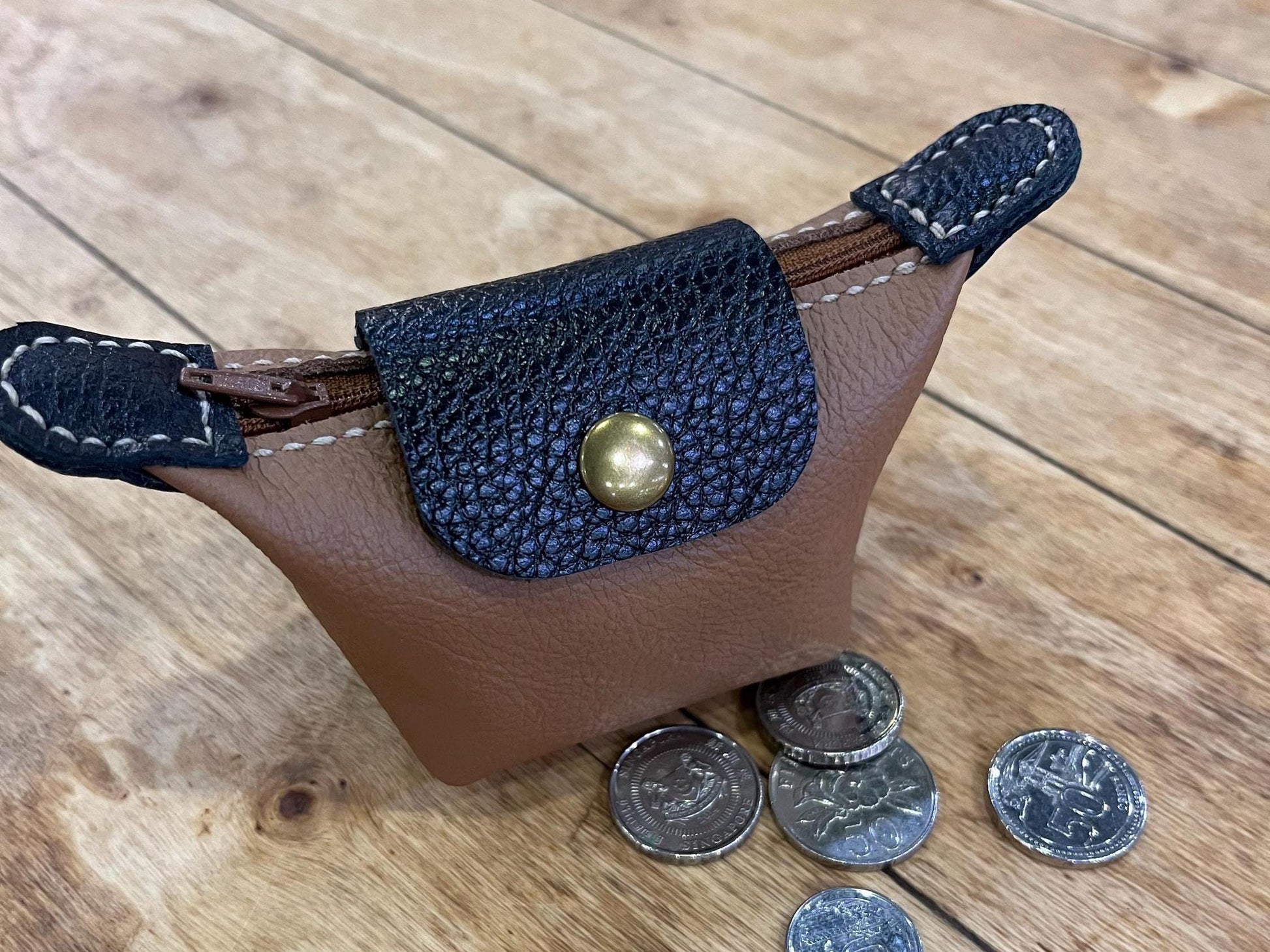 Elegant leather mini purse with coin on wooden table