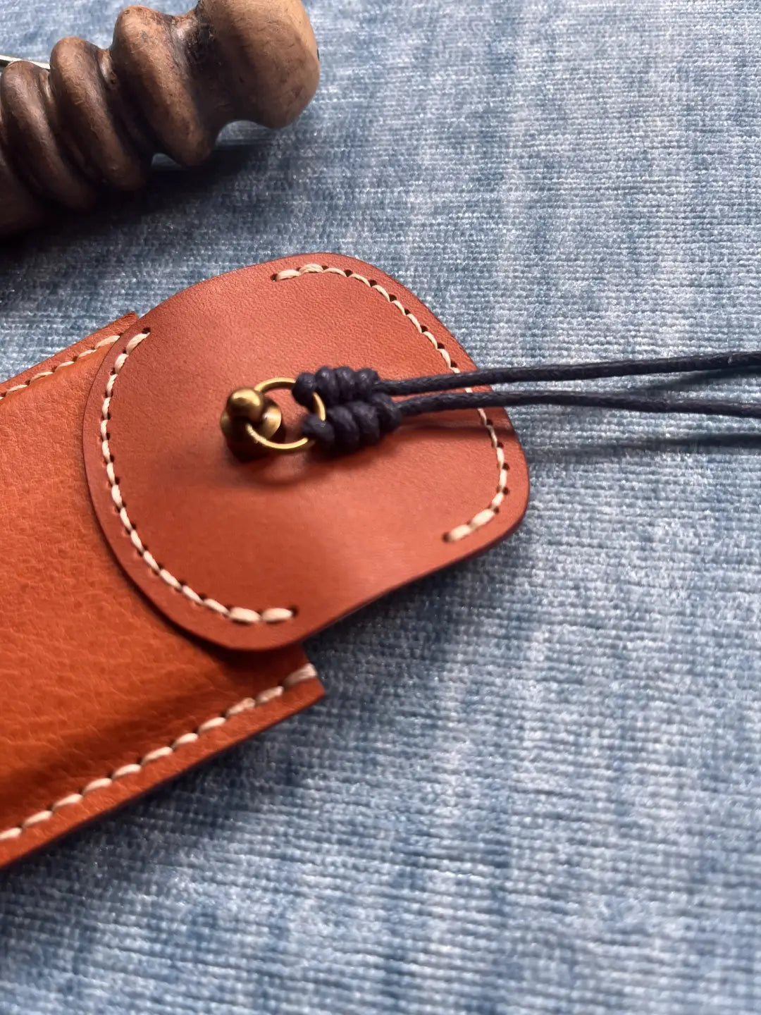 The back side of a handmade leather card sleeve showing clean, consistent saddle stitching and high-quality leather grain.