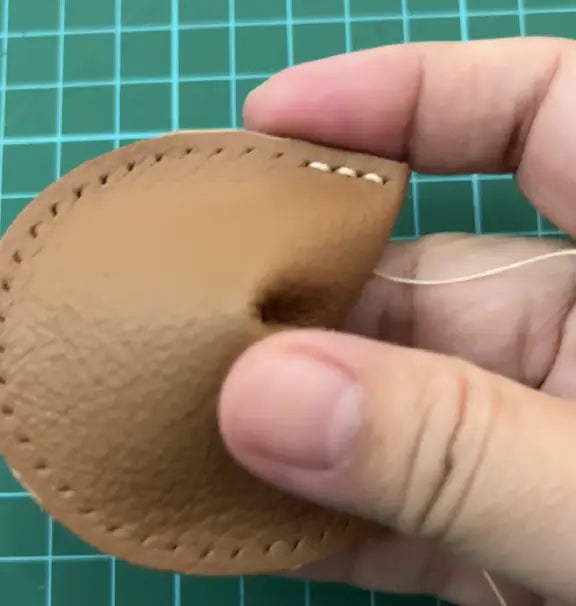 hand sewing of leather fortune cookie keychain.