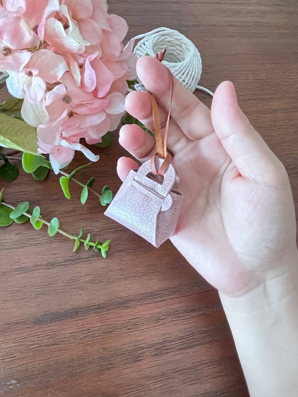 Mini leather pouch held in hand showing the 4cm small scale size of the bag charm.