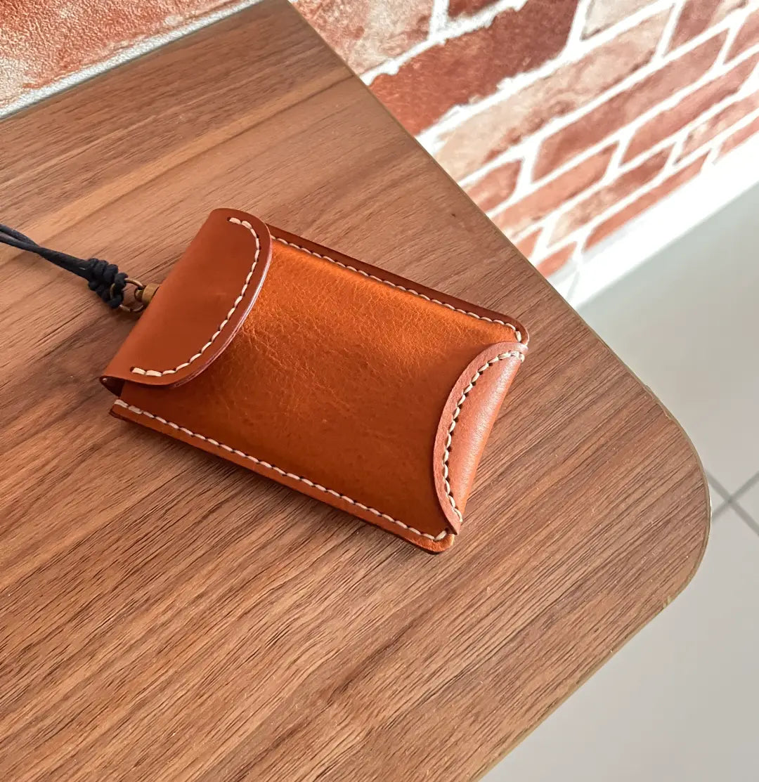 Side view of a slim leather card holder showing the thin profile and burnished edges of vegetable tanned leather.