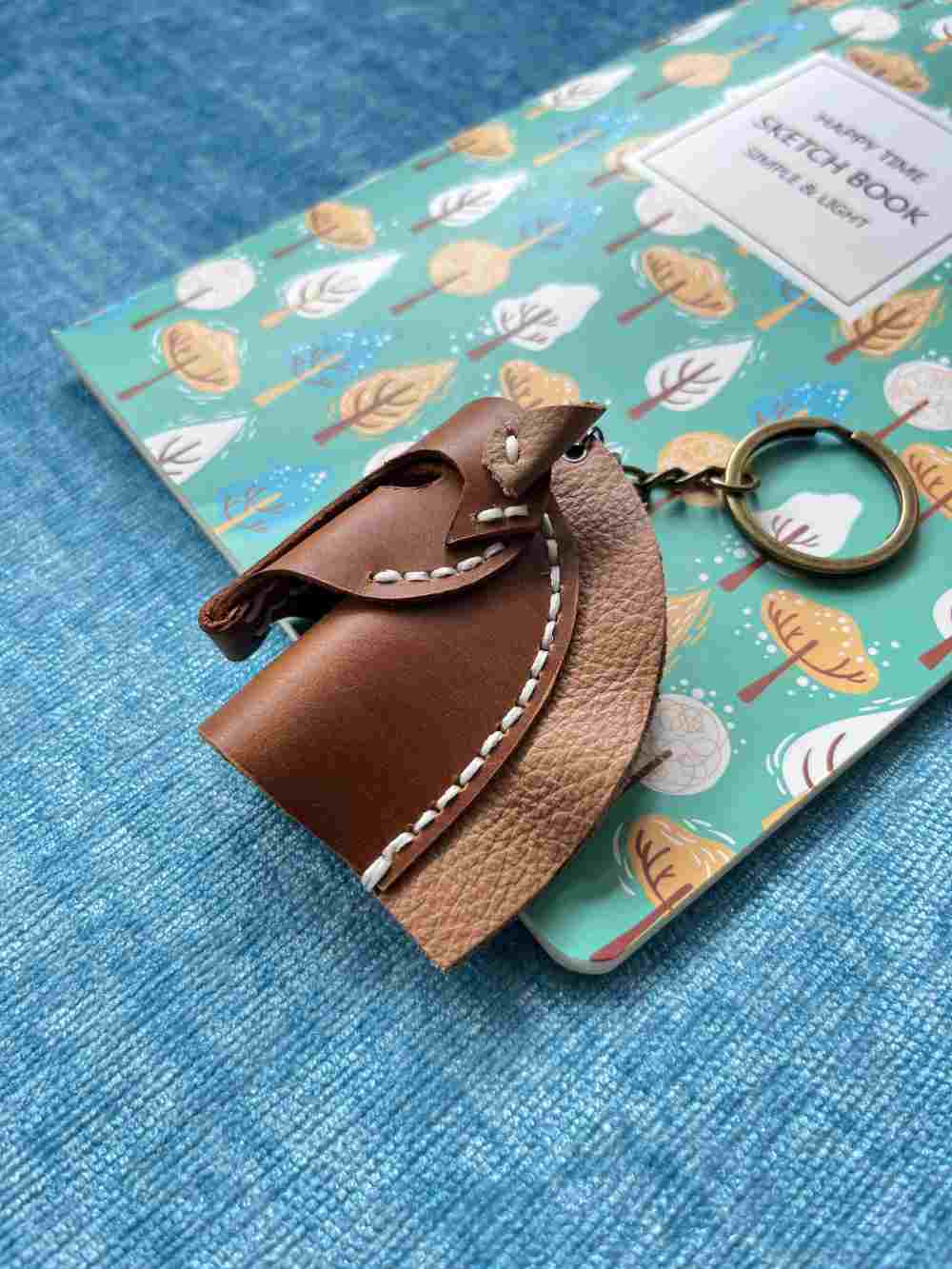 Close-up of a saddle-tan leather pony charm with detailed contrast stitching.