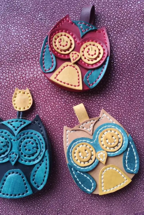 Three colorful leather owl ornaments featuring intricate layered circles and contrast stitching.