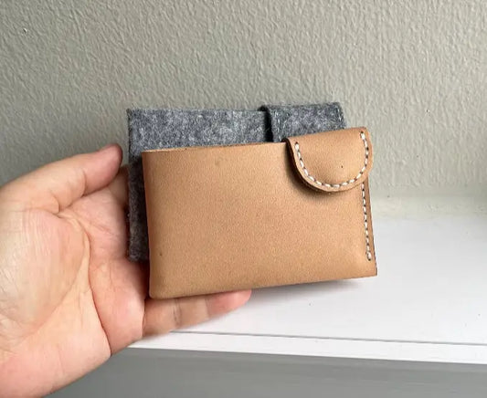 Modern aesthetic leather card holder with sleek lines and snapping button.