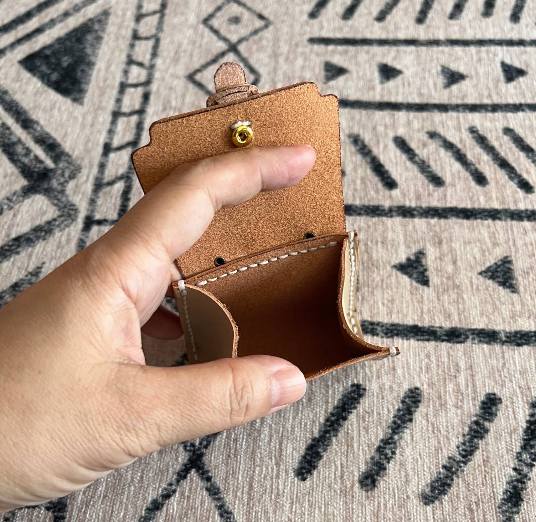 Top view of the leather tiny bag open, showing the internal space for earbuds or coins. 