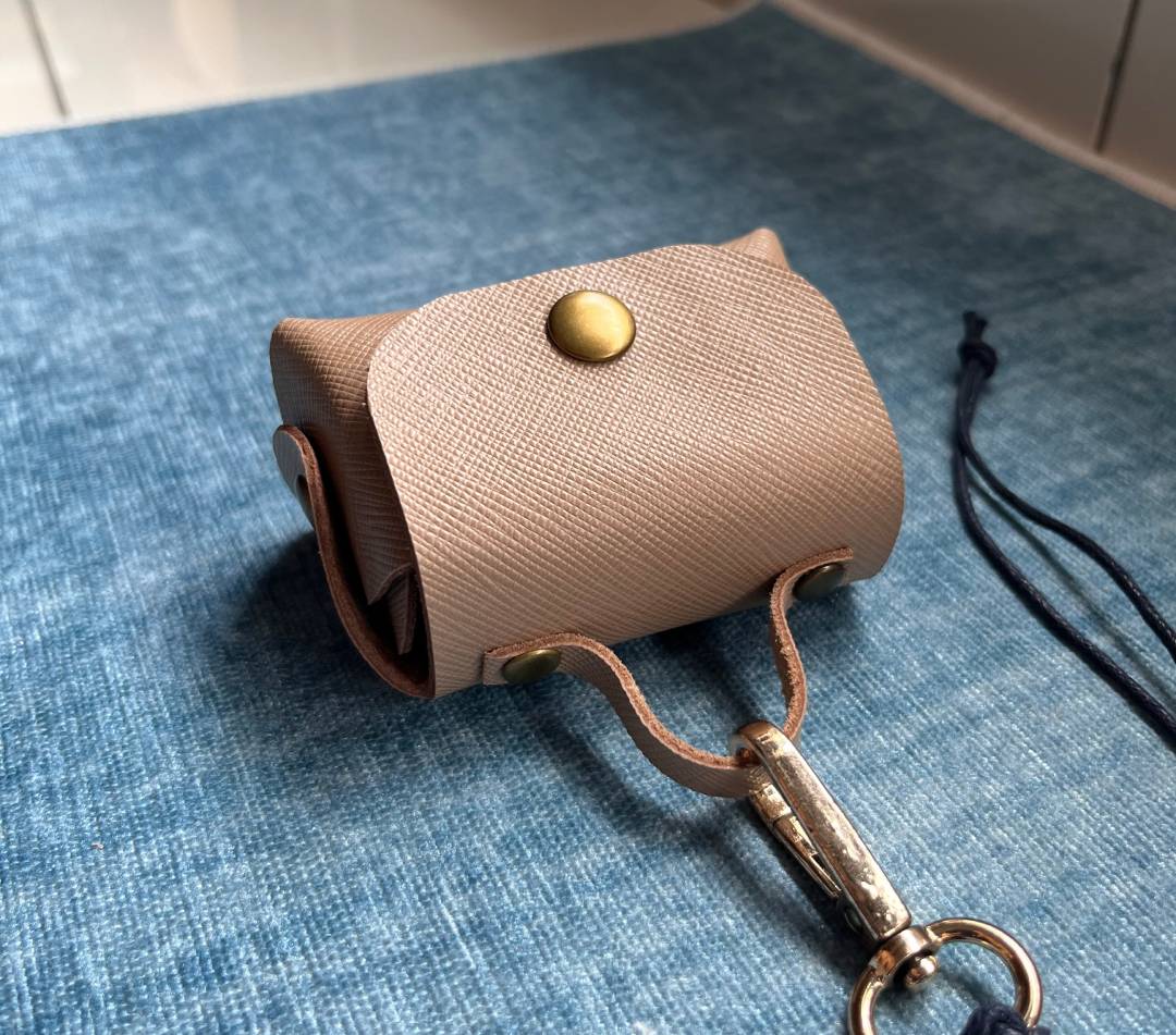 Front view of a luxury-style mini leather satchel for AirPods Pro.