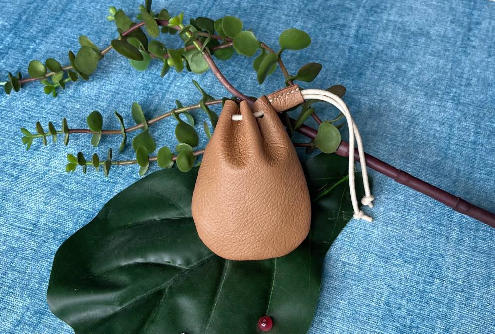 Small budget bag made from odd-shaped leather scraps with a drawstring top.