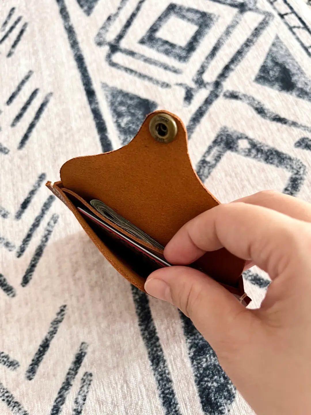 Interior view of a DIY brown leather wallet with a brass snap, showing the raw suede underside and simple construction for beginners.