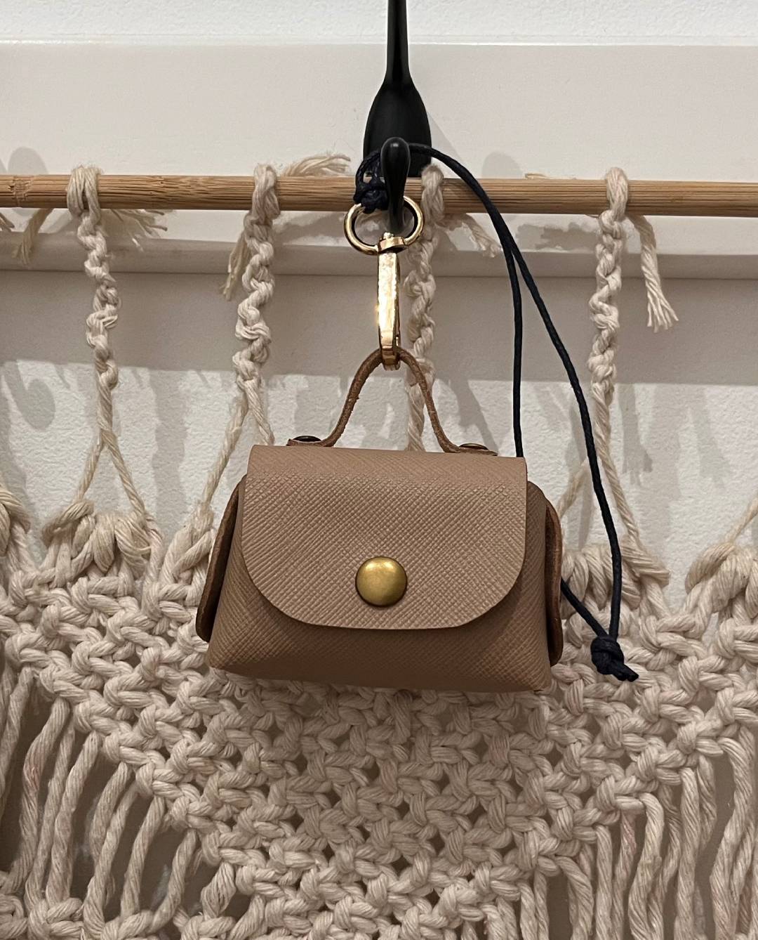 Close-up of a no-stitch leather  Air Pod Pro case with a gold snap button 