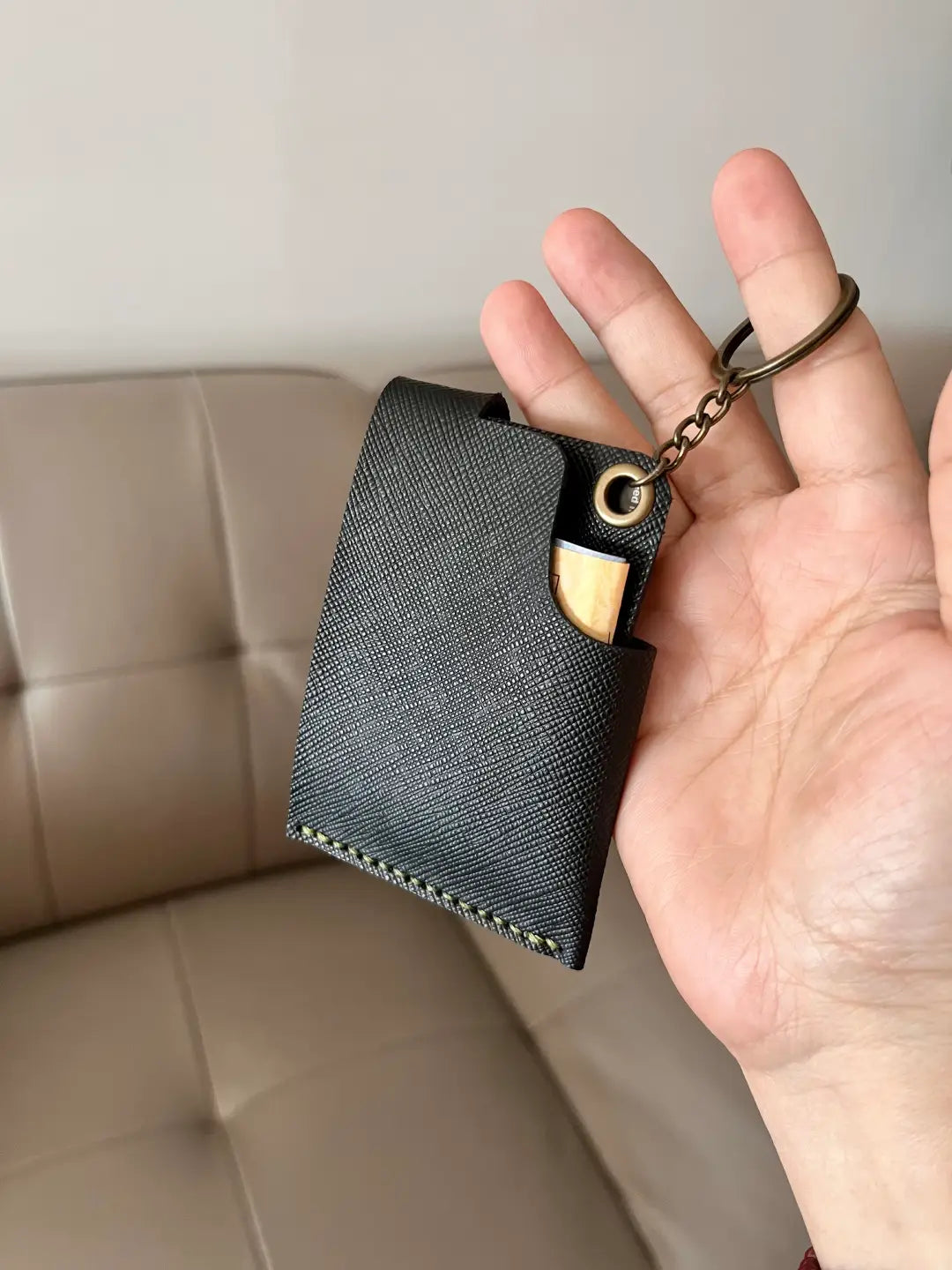 A hand holding a handmade navy blue leather multi-function wallet with a brass snap closure