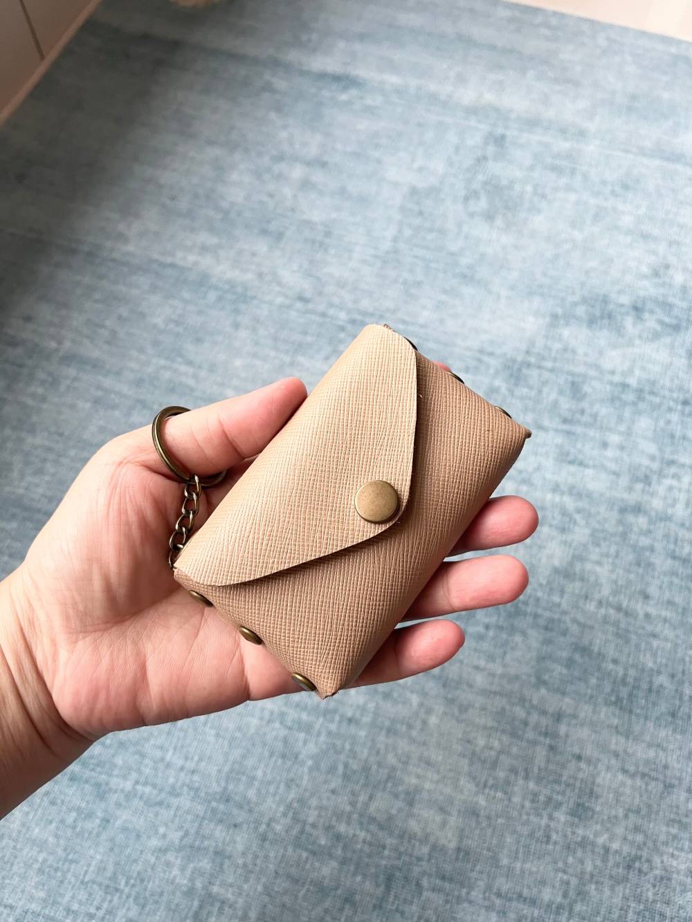 Hand holding a 10cm leather wallet to show compact minimalist size.