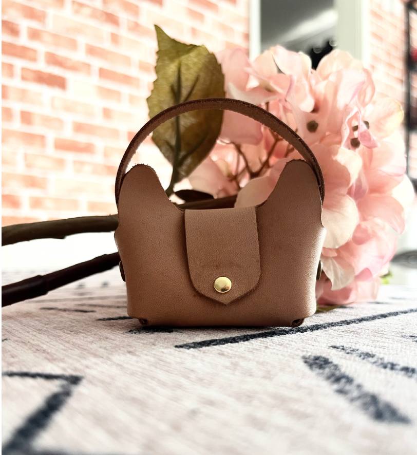 Tan leather no-sew bag charm pouch with gold snap button hanging on a larger bag.