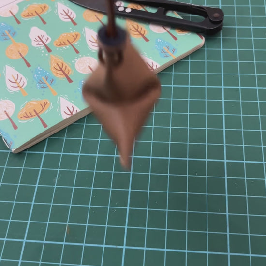 A brown handmade cookie-shaped decorative charm using leather.