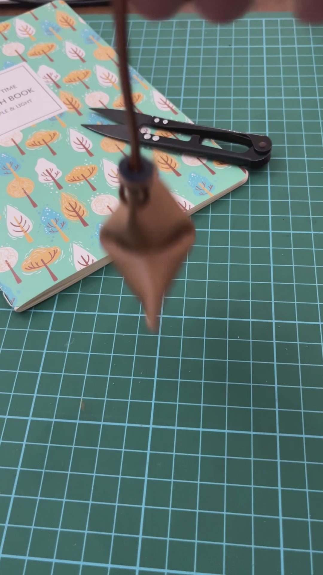 A brown handmade cookie-shaped decorative charm using leather.