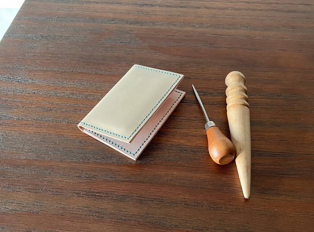Slim Leather card holder with leather crafting tools on a wooden surface