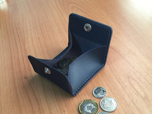 square leather pouch with a snap closure designed for coins and small accessories.